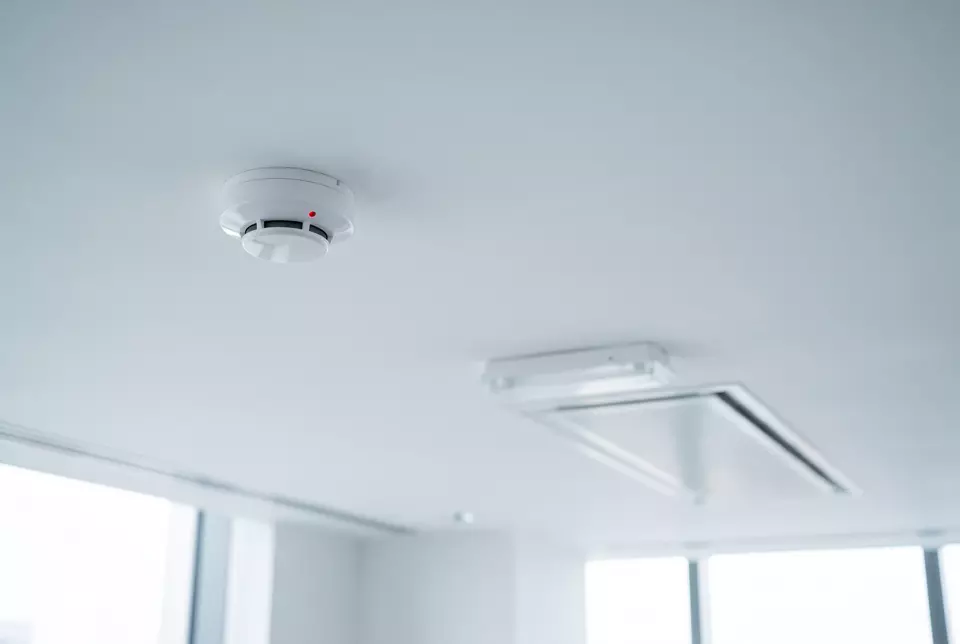 A smoke detector and emergency light on an office ceiling